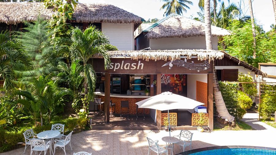 Splash Pool Bar at Coral Reef Resort & Spa in Havelock featuring wooden facade with a sign reading  Splash located near a pool area. The surroundings feature tropical plants and a relaxing outdoor seating area - Coral Reef Resort & Spa, Havelock