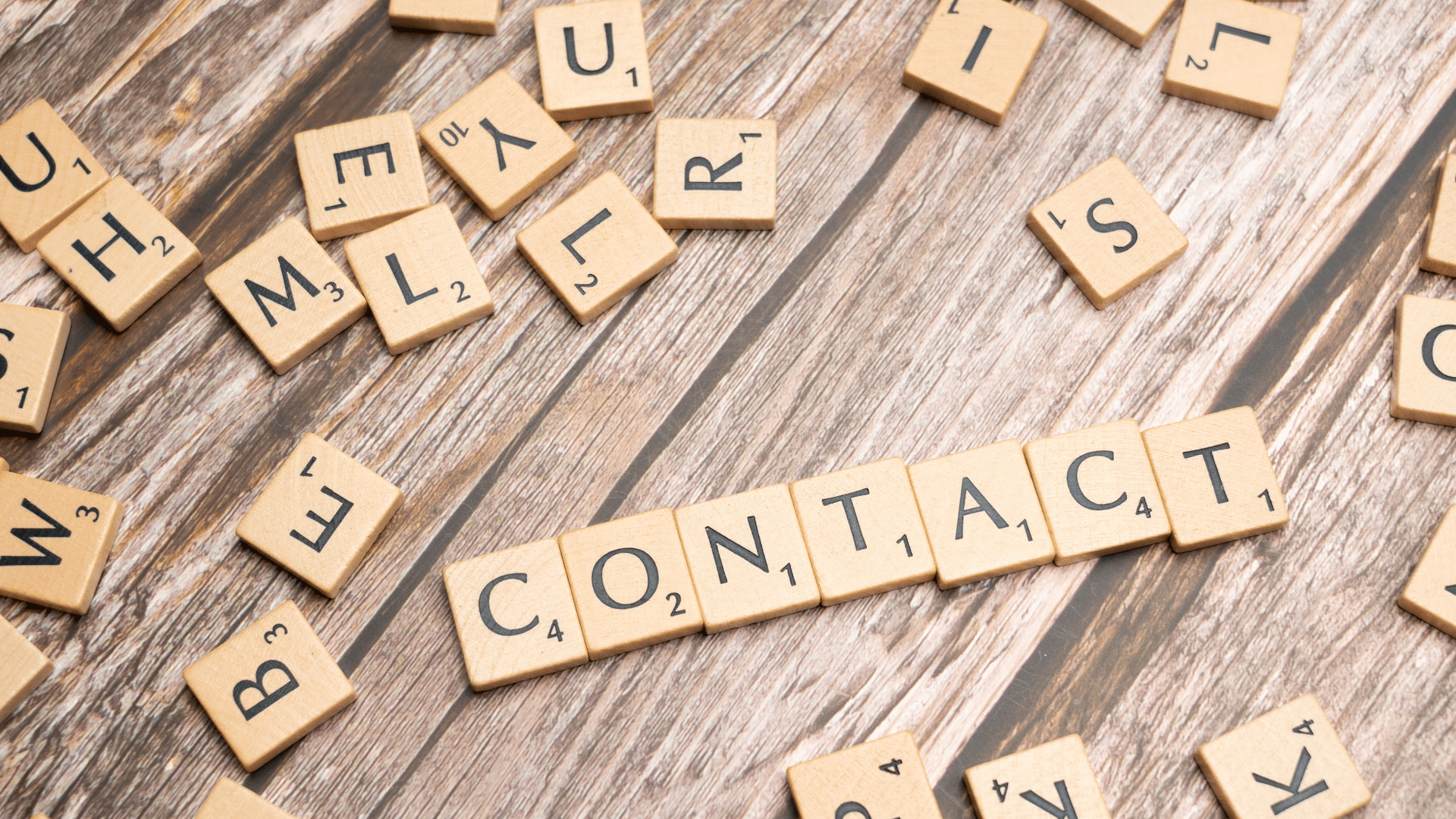 Scrabble tiles spelling the word contact on a weathered wooden surface