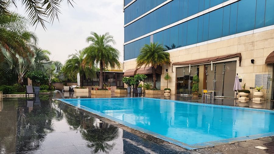 An image of a swimming pool surrounded by some palm trees in the property of Golden Suites Gurgaon