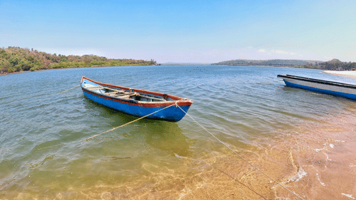 A fishing boat in Querim Beach on the shores with land in the background