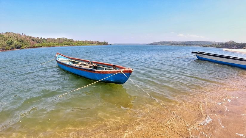 A fishing boat in Querim Beach on the shores with land in the background