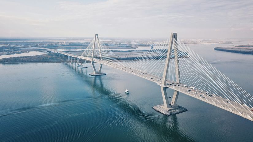 A hanging bridge connecting two lands separated by an ocean with blue sky in the background