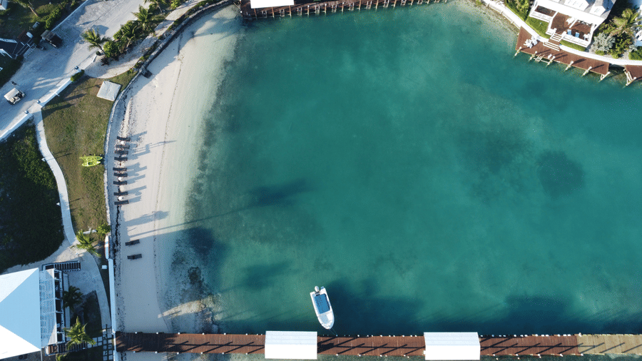 Aerial view of beach near Abaco Inn, with turquoise water, sandy shoreline, dock, and palm?lined resort pathways creating a serene coastal escape.