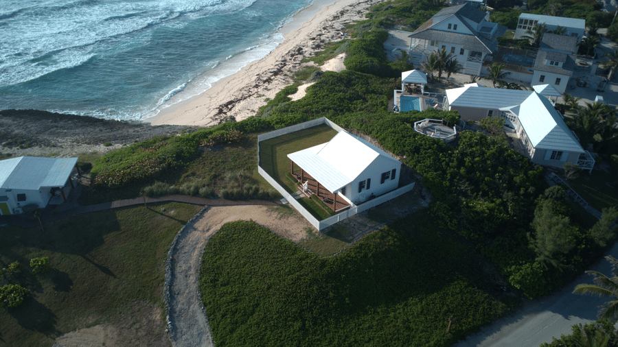 Aerial view of Hill Top Cottage near Abaco Inn, showcasing coastal charm, lush greenery, and seaside architecture in a serene island setting.