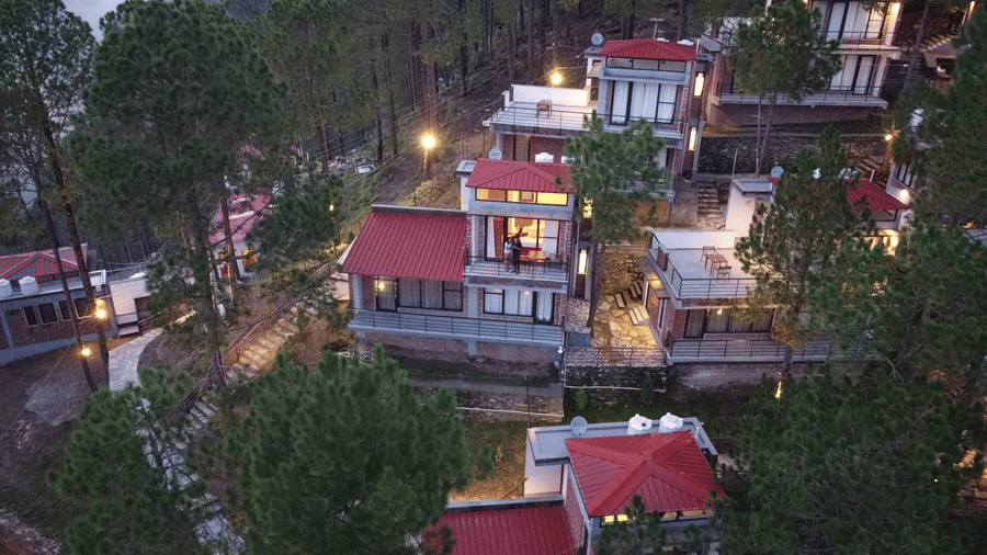 Aerial view of BluSalzz Escapade Resort, Lansdowne featuring buildings adjoining each other and is set amidst the green hills.