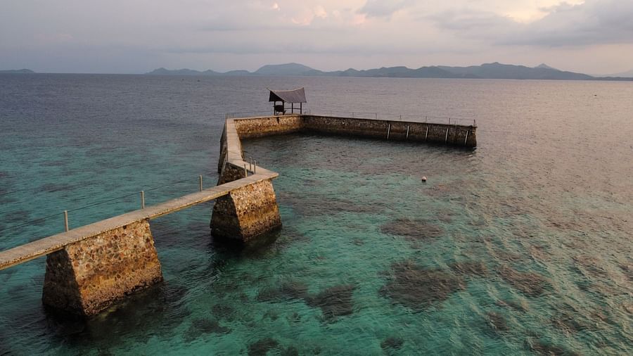 Pier extending into the ocean with Flower Island Resort buildings at the shore.