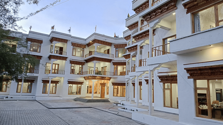 Wide-angle facade view of Indus Serenity Retreat with a central courtyard, white exterior walls, and mountain-style wooden detailing.