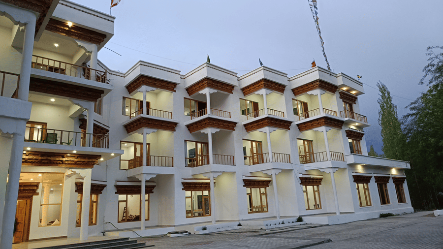 Front-facing view of Indus Serenity Retreat showcasing the contemporary Himalayan-style architecture with spacious balconies and illuminated interiors.