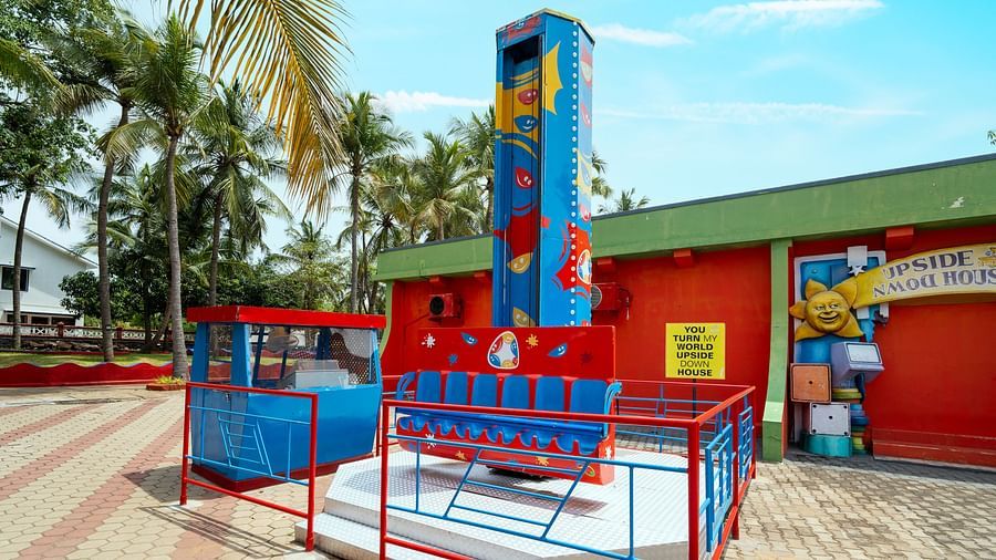 Colourful kids' Graffity tower ride at MGM Dizzee World, set against a vibrant red building with palm trees in the background.