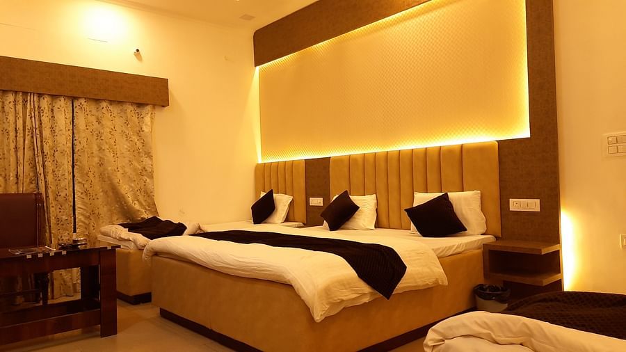 A suite in Roorkee with warm yellow lights, a king size bed, a single bed and a teapoy - Motel Divine International, Roorkee