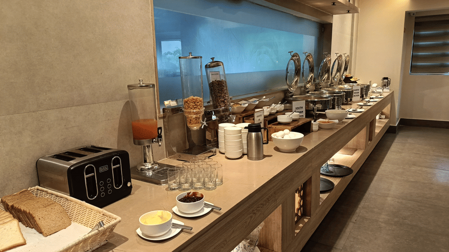 A breakfast buffet counter with a toaster, cereal dispensers, and various serving dishes
