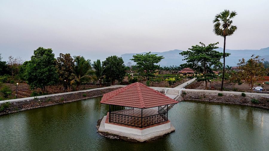 Artificial pond at The Kanila Resort featuring a hut in the middle of it with backdrop of misty mountains.