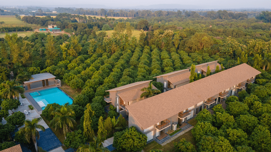 A panoramic aerial view at Wyndham Garden showing a long low-rise building and a separate pool area surrounded by a grove of trees.