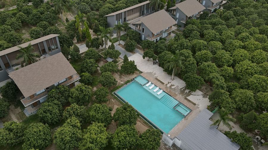 Aerial view of a rectangular swimming pool amidst dense greenery with villas arranged symmetrically around it at Wyndham Garden.