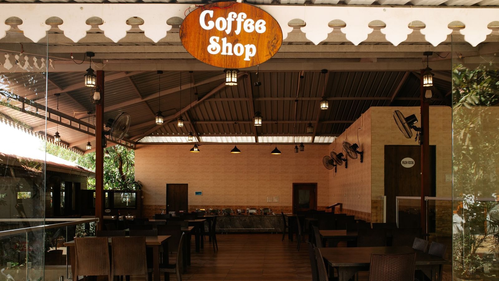 An empty Coffee Shop with many tables under a covered outdoor area, at Daksh Resort & Amusement Park, Sasan Gir.