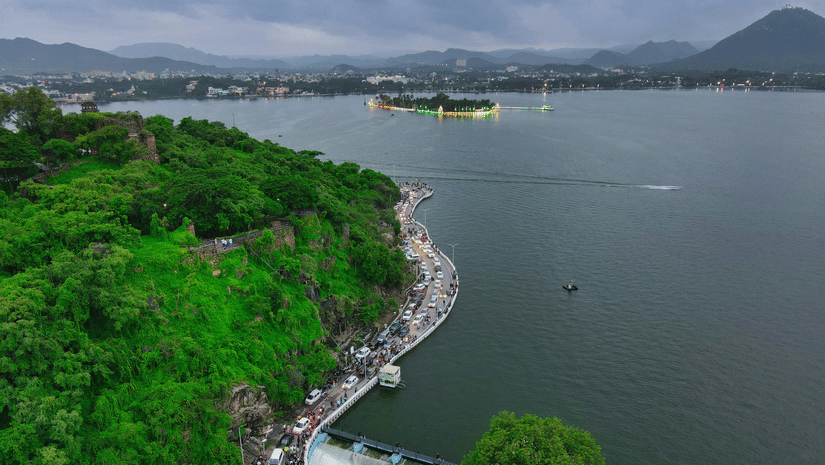 Aerial view of the curved, tree-lined promenade along the scenic Fateh Sagar Lake in Udaipur.