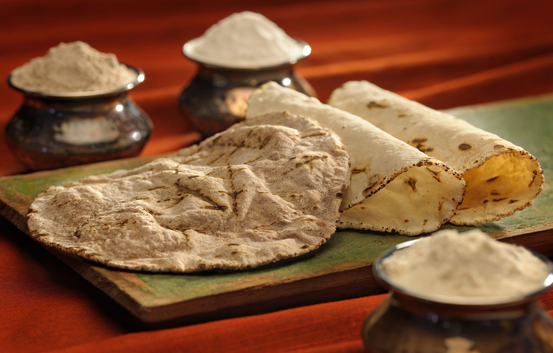 Traditional Indian flatbreads and flour in steel pots.