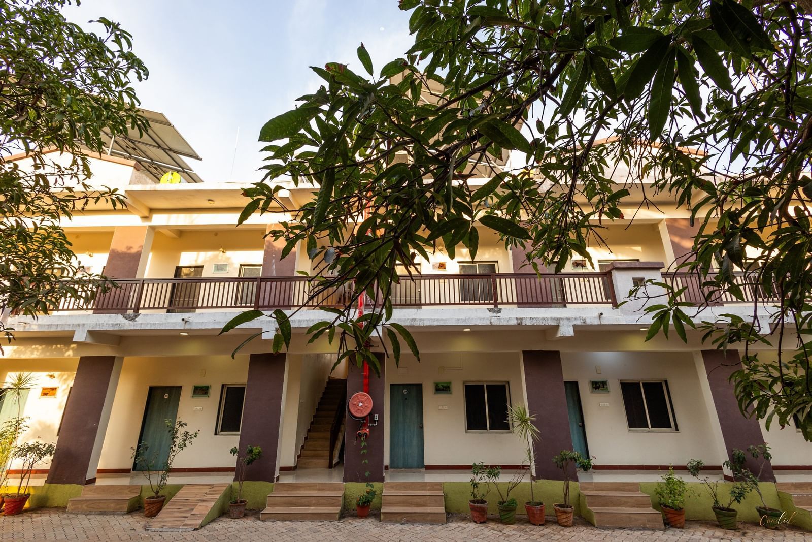 A view of the facade featuring rows of guest rooms with a wide balcony area surrounded by greenery at Daksh Resort and Amusement Park.