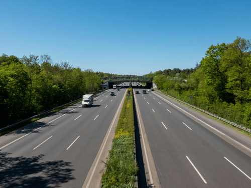 An overview of a 6-lane highway with trees on either side of the road and a manicured bush in the centre, as seen during a Goa trip from Pune.