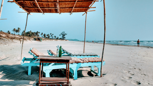 An overview of a beach shack in Goa with a lounger and a makeshift roof with trees in the distance.