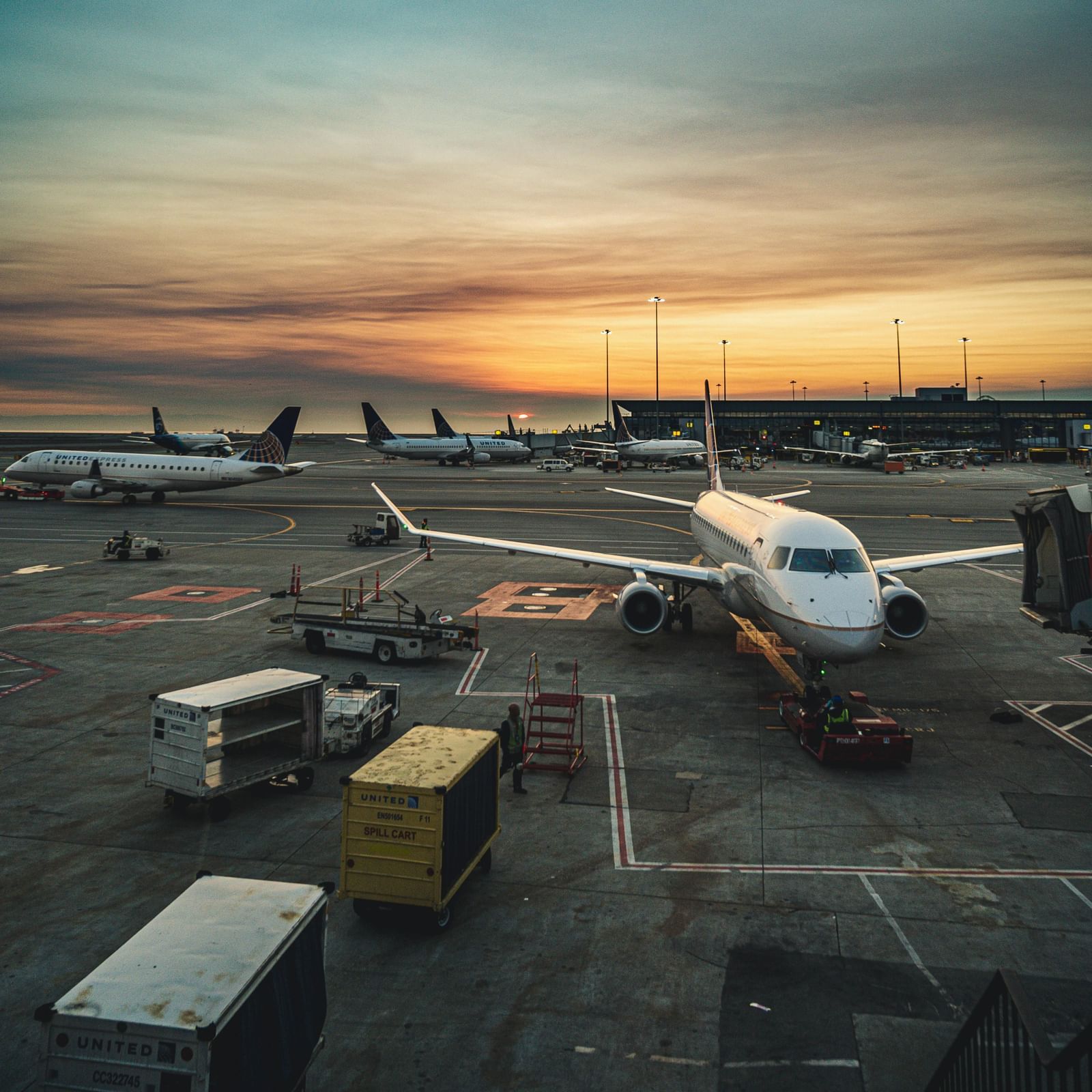 An image of an aeroplane standing in the airport with the backdrop of a sunset