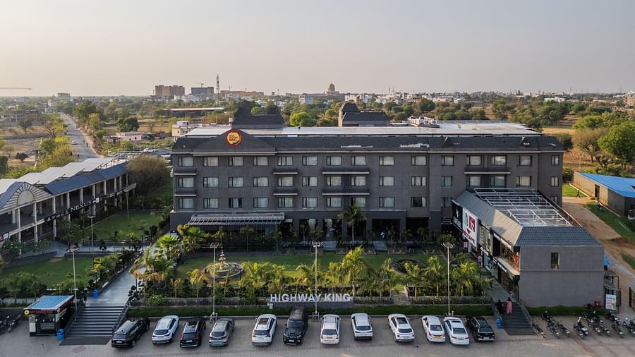 Aerial view of Hotel Highway King, Bagru, with landscaped gardens, parking area, and surrounding buildings in the background.