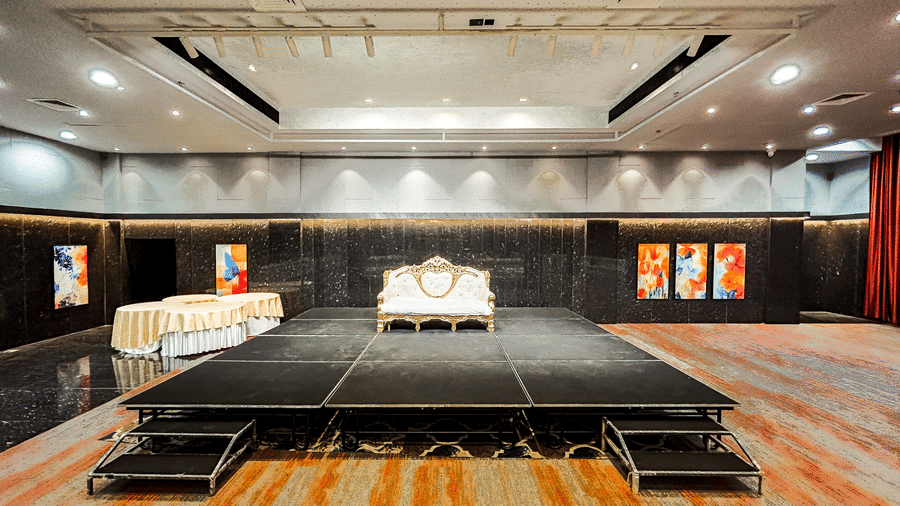 Carpeted banquet hall with a huge stage, ceiling lights, and wall decor at Infiniti Hotel, Indore.