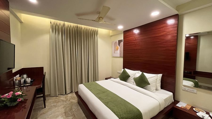 An image of a Deluxe room featuring a king size bed, bedside table on either side, flat TV screen, tea and coffee maker on a work a desk desk, and a chair - Five Elements Hotel, Jodhpur