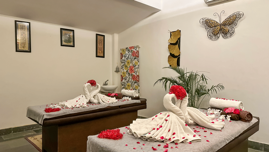 A spa treatment room featuring two massage beds decorated with towel art and flower petals | Anandam Jungle Retreat Resort, Udaipur