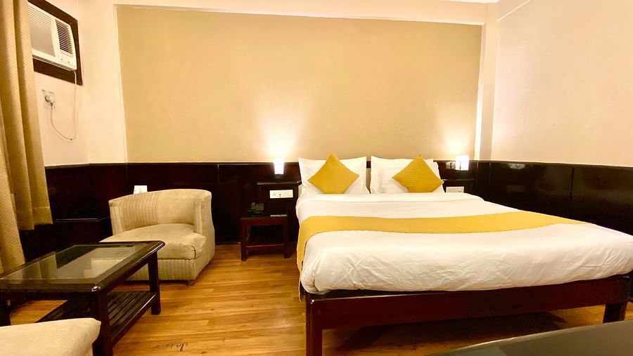 A bedroom with a cushioned chair and a coffee table beside it at DLS Park Grace, Haridwar.