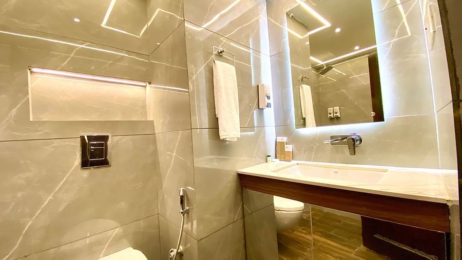 A bathroom with a mirror and illuminating light at DLS Park Grace, Haridwar.