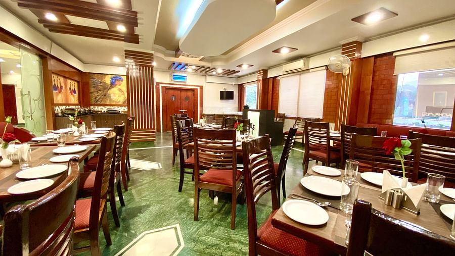 A spacious restaurant interior with multiple tables and chairs arranged in rows | DLS Park Grace, Haridwar