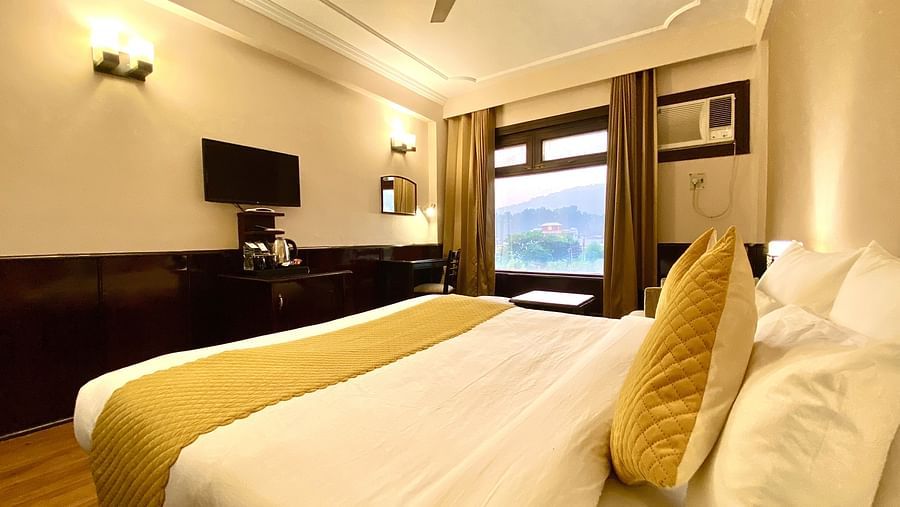 Side view of a bedroom with warm yellow lights highlighting the walls around a mounted television, at DLS Park Grace, Haridwar.