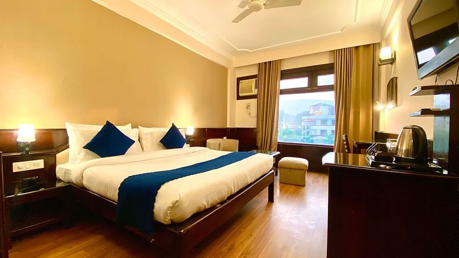 A bedroom with a ceiling fan and windows covered by curtains at DLS Park Grace, Haridwar.