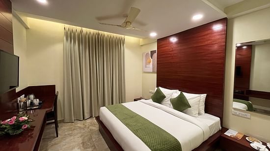 An image of a Deluxe room featuring a king size bed, bedside table on either side, flat TV screen, tea and coffee maker on a work a desk desk, and a chair - Five Elements Hotel, Jodhpur