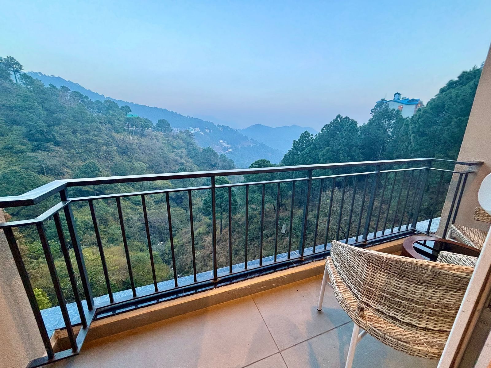 Balcony view with a chair overlooking lush green hills and a serene valley at ARNISA Boutique Hotel