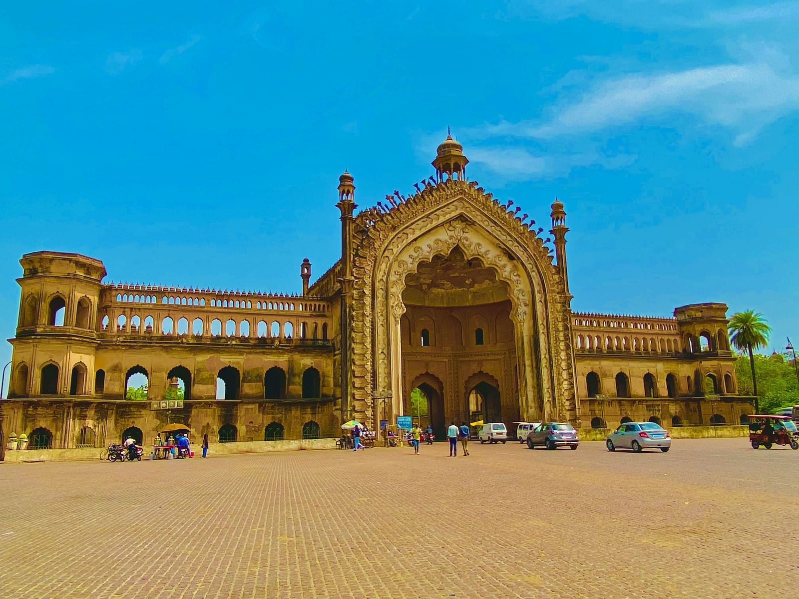 The historic Rumi Darwaza in Lucknow, a grand Mughal-style gateway with intricate architecture, standing against a vibrant blue sky.
