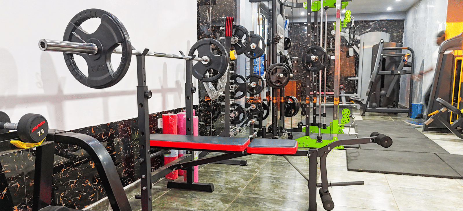 Interior view of a gym with weight racks, barbells, and exercise equipment - Luffu Club