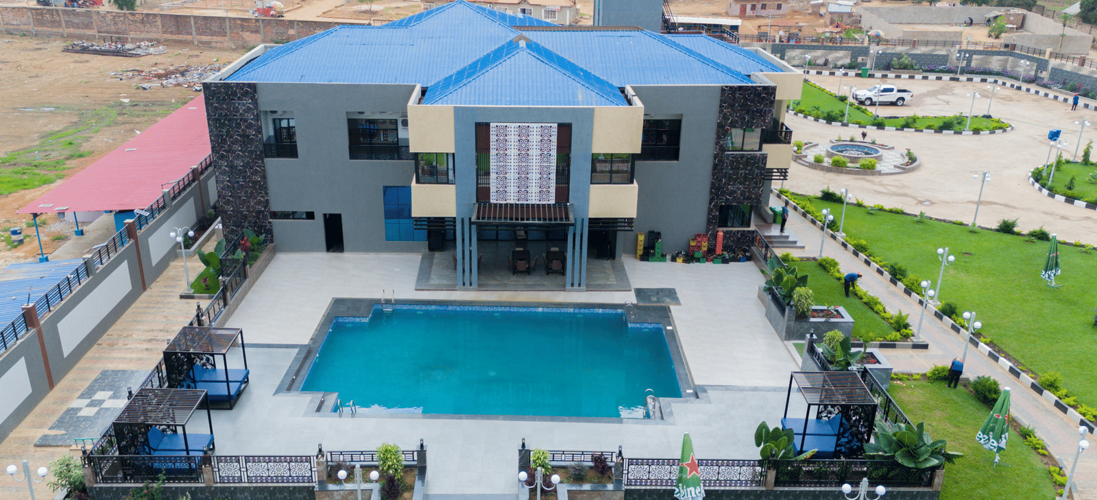 Aerial view of a modern building with a swimming pool and landscaped grounds - Luffu Club