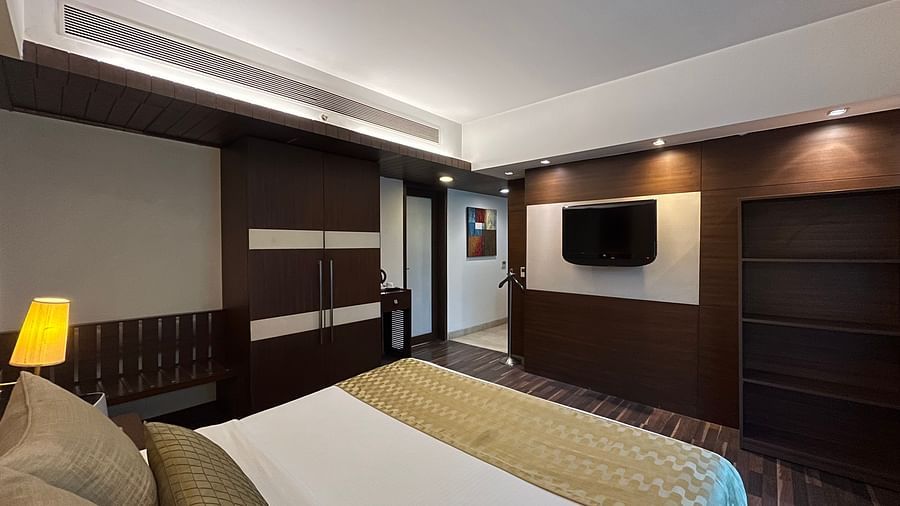 a cosy bedroom with king size bed and room amenities like a wardrobe television air purifier and wooden interior - yuhi mansions suite room1