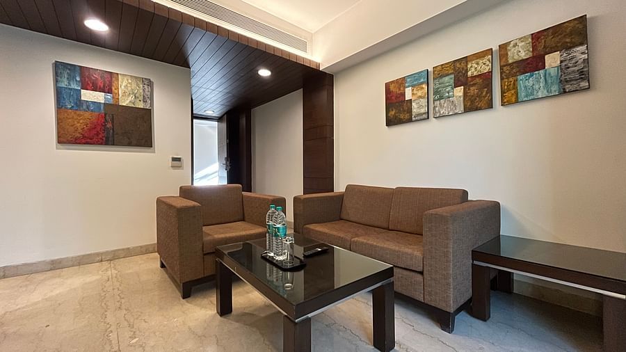 teapoy and brown colour couch inside a suite room with wall paintings in the background - yuhi mansions