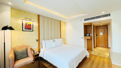 Well-appointed standard room at Nemesia with a comfortable bed, a seating area, and a view of the city.