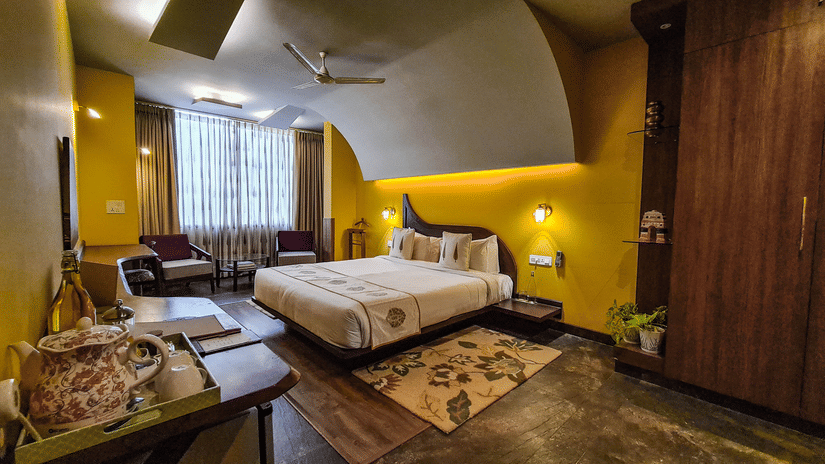 A bedroom at Ekaa Agra featuring a bed, seating area, wooden interiors, and warm ambient lighting.