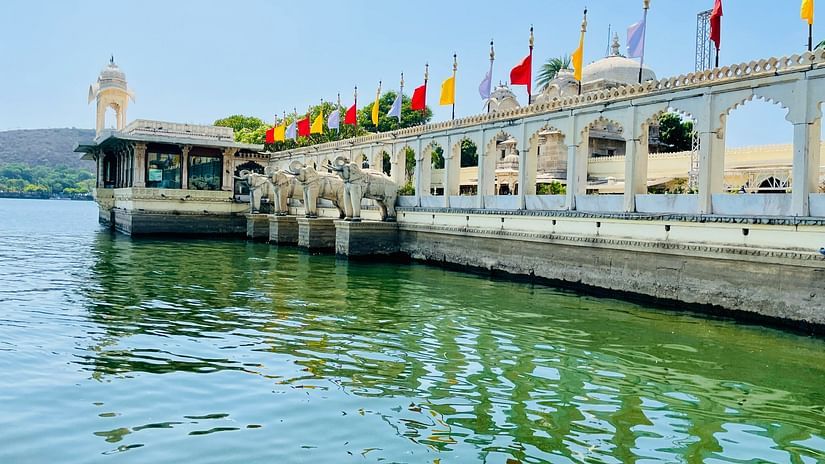 A side view of Jag Mandir with lake Pichola also in view and blue sky in the background
