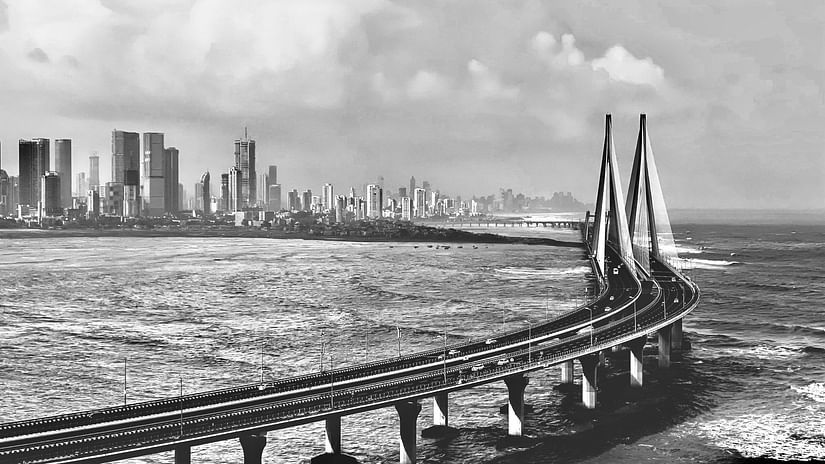 An aerial view of bandra worli sea link bridge in black and white with buildings in the background.