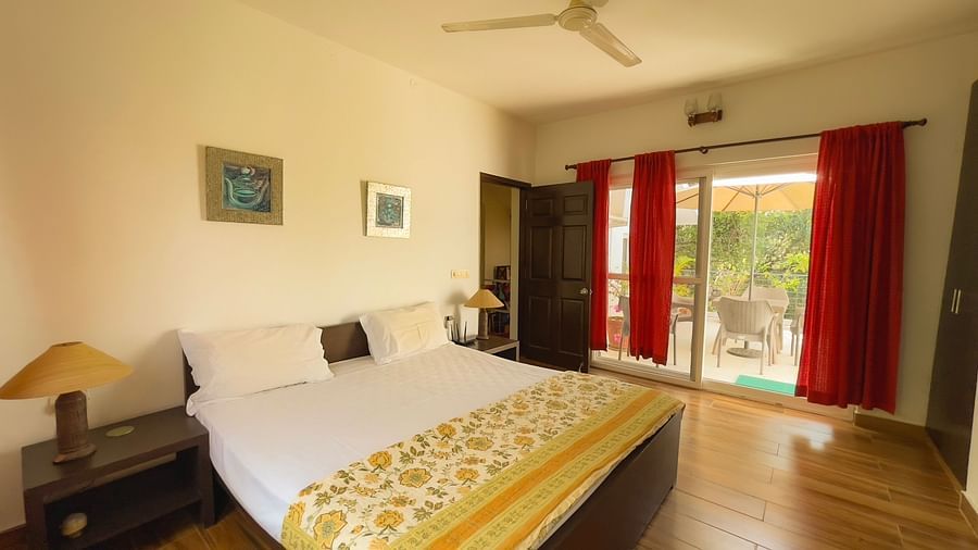 King bed with lamp on side table and access to balcony at el benito goa