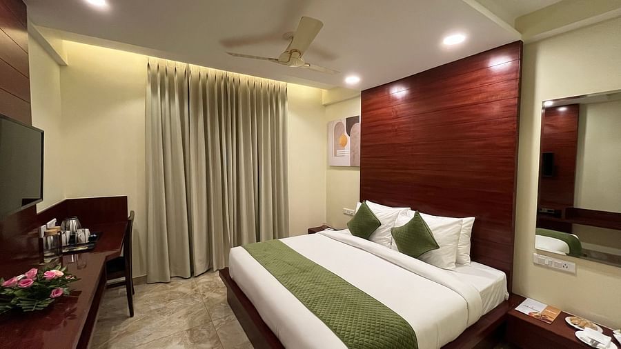 An image of a Deluxe room featuring a king size bed, bedside table on either side, flat TV screen, tea and coffee maker on a work a desk desk, and a chair - Five Elements Hotel, Jodhpur