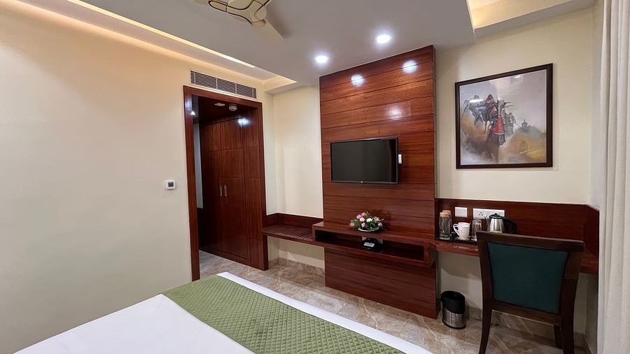 An image of a deluxe room featuring a bed, a flat TV screen, a work desk and chair, and a fan on the ceiling - Five Elements Hotel, Jodhpur