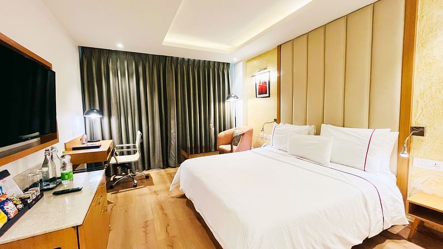 Spacious standard room at Nemesia featuring a comfortable king-size bed, a work desk, and a seating area. The room is decorated with warm tones and modern furnishings.