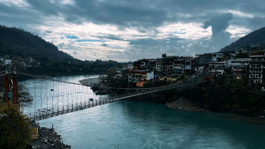 Suspension bridge crossing a river with a town on the other side.
